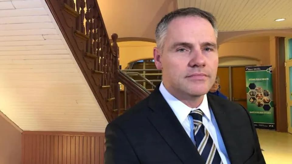 A man posed for a photo in a suit, indoors.