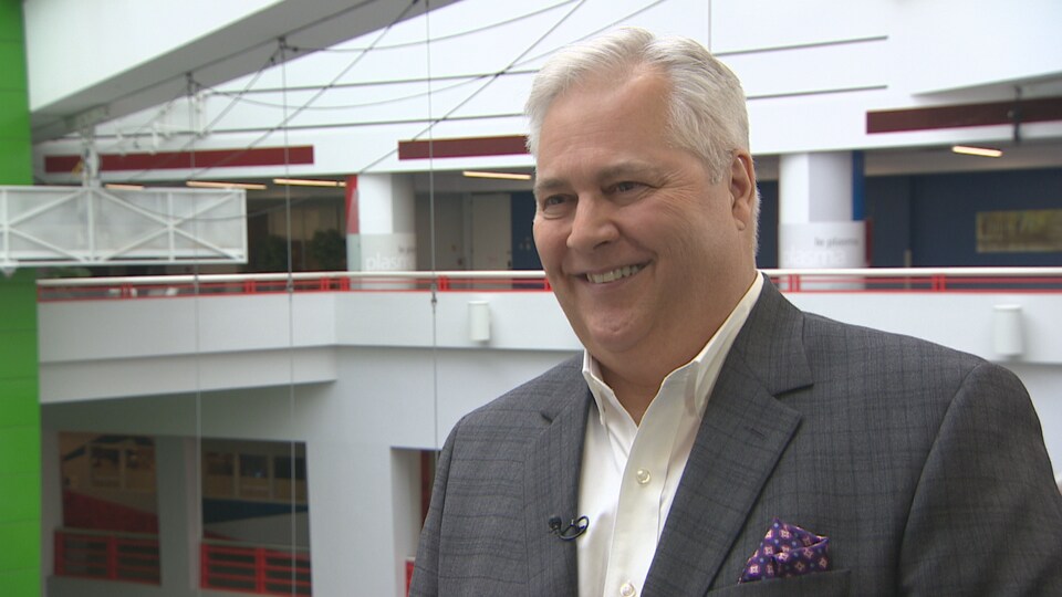 Paul Dubé répond au question de la journaliste devant l'atrium de Radio-Canada.