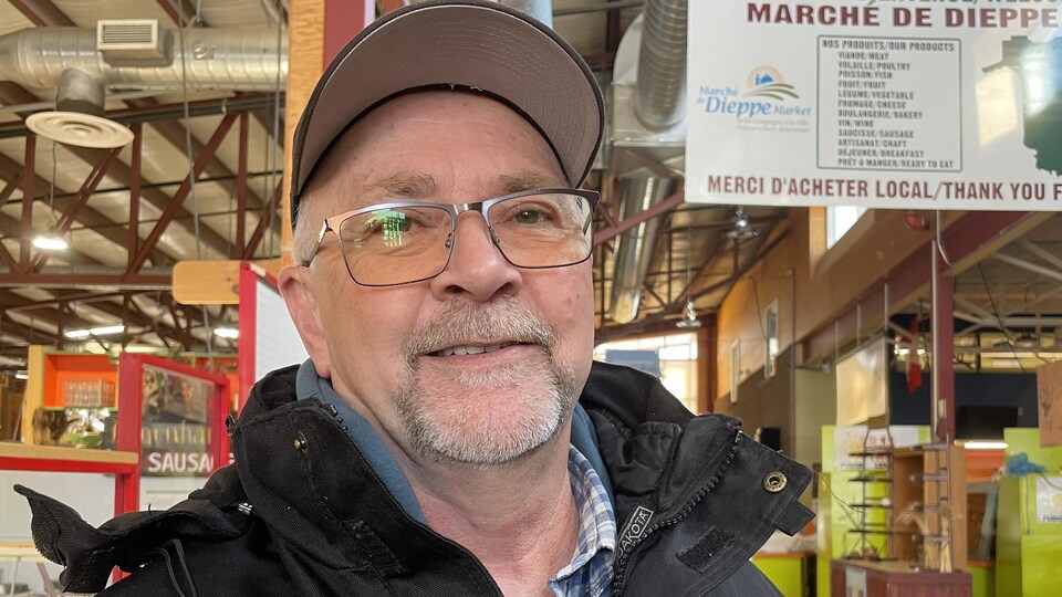 Paul-Émile Doucet sourit et pose pour une photo à l'intérieur du marché public.
