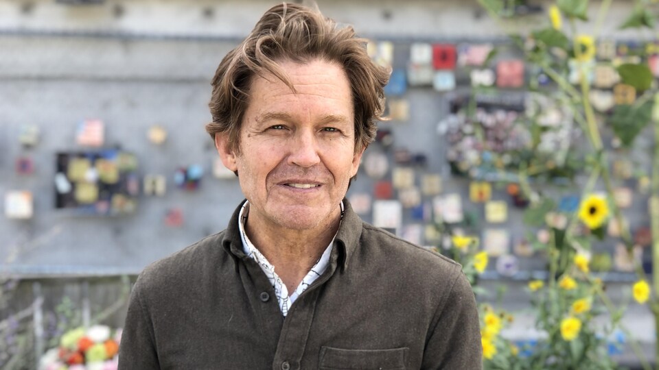 Paul McClure in front of a wall with pieces of tiles.