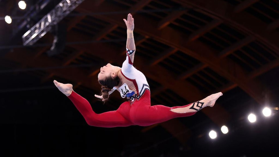 Une femme fait le grand écart en l'air.