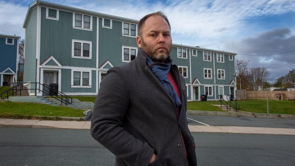Doug Pawson devant des logements modestes.