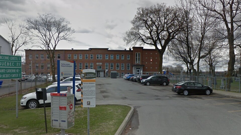 L'édifice est visible à partir de la rue. On voit un stationnement en premier plan.