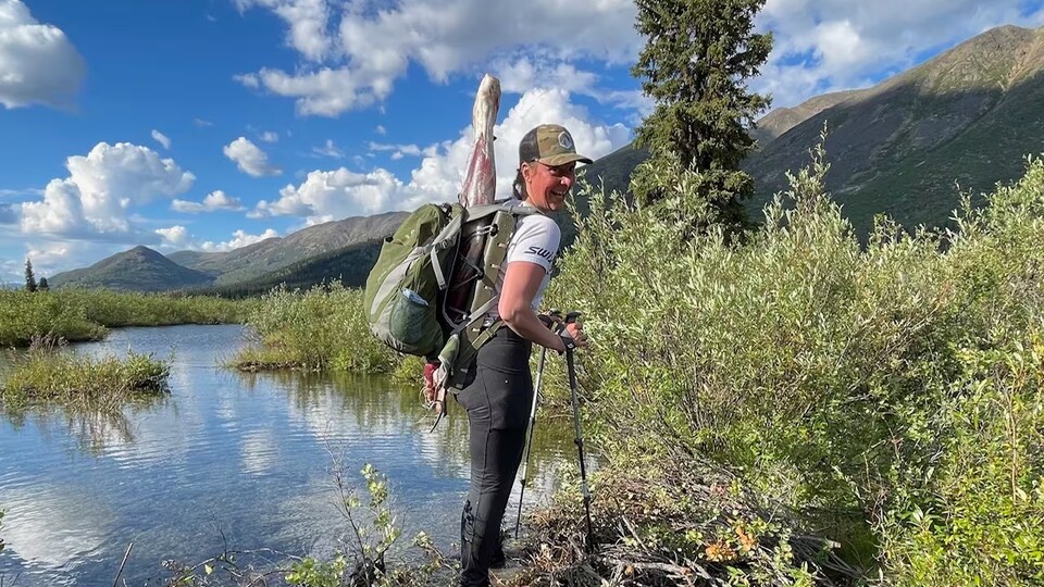 Pavlina Livingstone-Sudrich avec un sac à dos de randonnée en pleine nature, près d'une étendue d'eau.