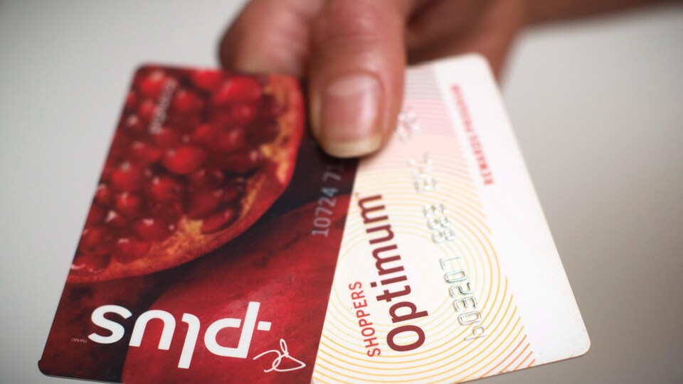 Photo d'une main qui tient les cartes PC Plus et Optimum.