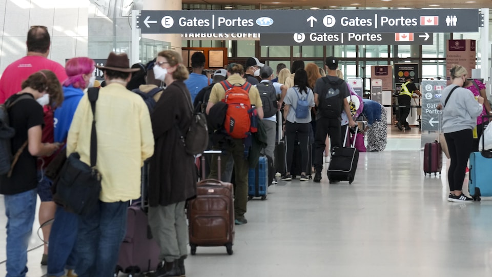 Des voyageurs attendant en file à l'aéroport Pearson de Toronto