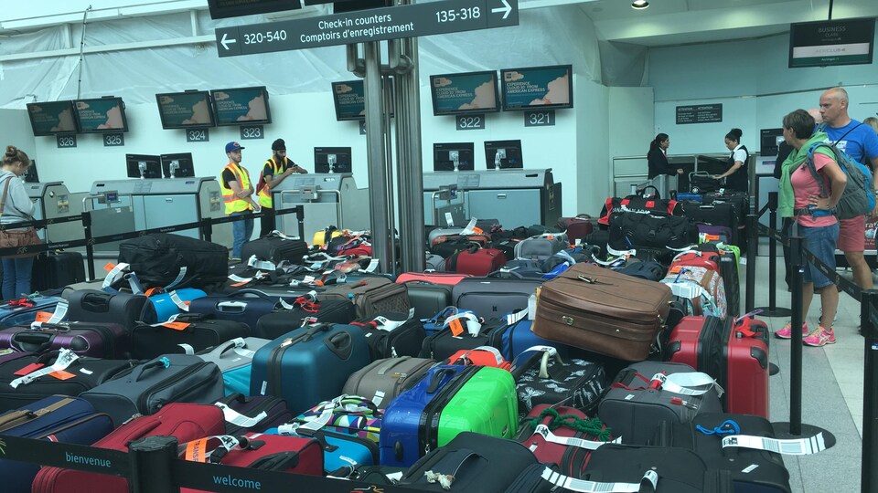Des valises s'accumulent près des comptoirs des départs à l'aéroport Pearson.
