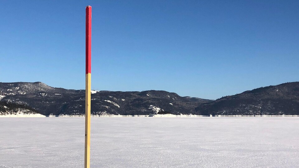 Une balise plantée dans la glace sur le fjord du Saguenay l'hiver.