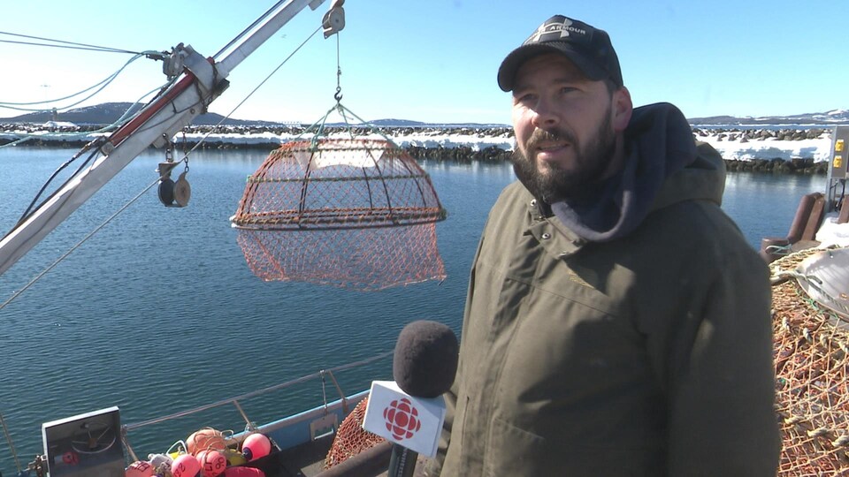 David Pelletier se tient devant un bateau de pêche, au quai de Sept-Îles