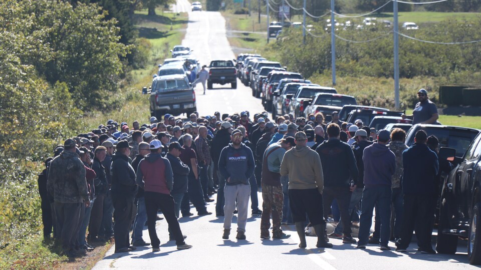 Des dizaines d'hommes manifestent sur une route.