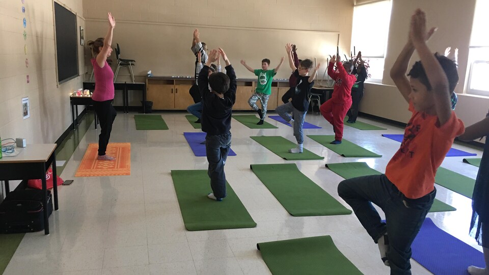 Des élèves se tiennent en équilibre sur des tapis de yoga