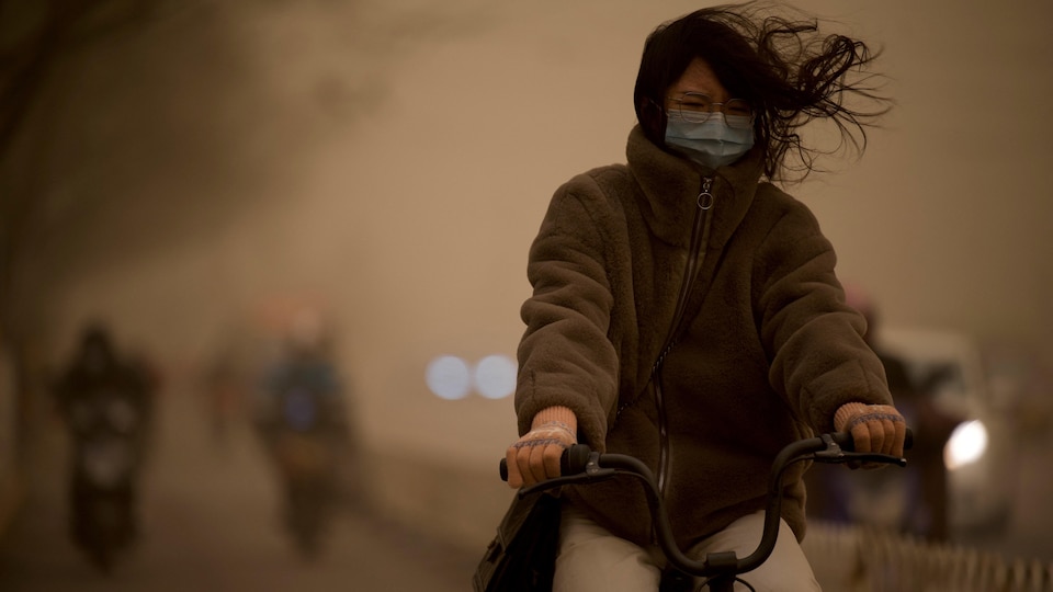 Une femme fait du vélo à Pékin.
