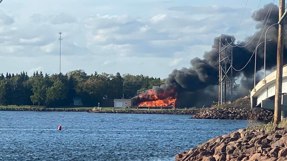 Un restaurant en flamme près d'un cours d'eau et d'un pont.