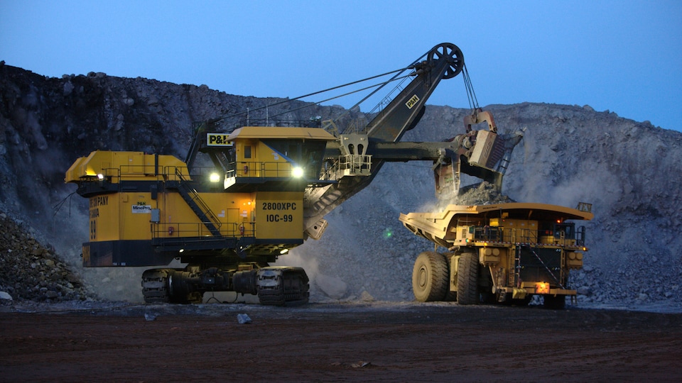 Une pelle mécanique et un camion dans un mine, de nuit.