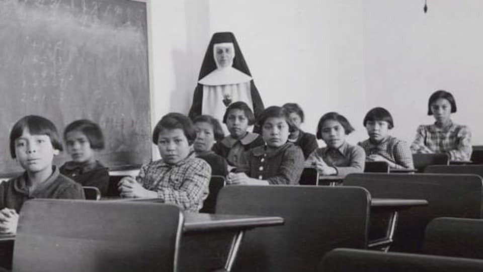 Students and nuns pose in a classroom at Cross Lake Residential School.