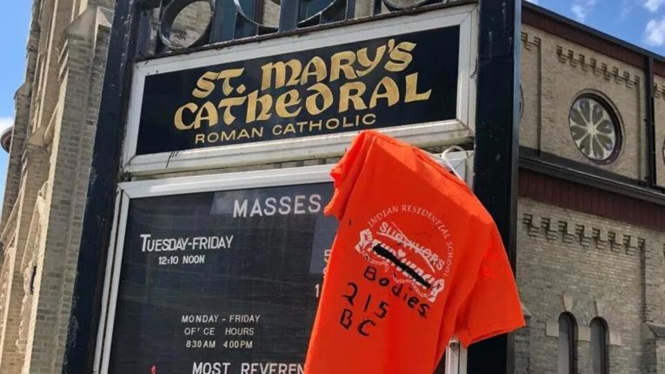 Un chandail orange accroché devant une église.