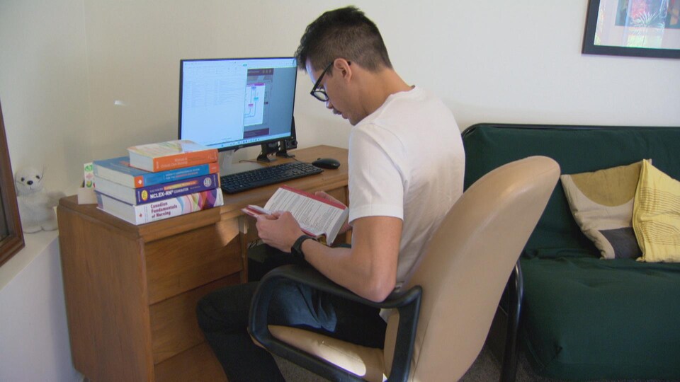 Laurent Chan en train d'étudier, devant son ordinateur et divers livres.