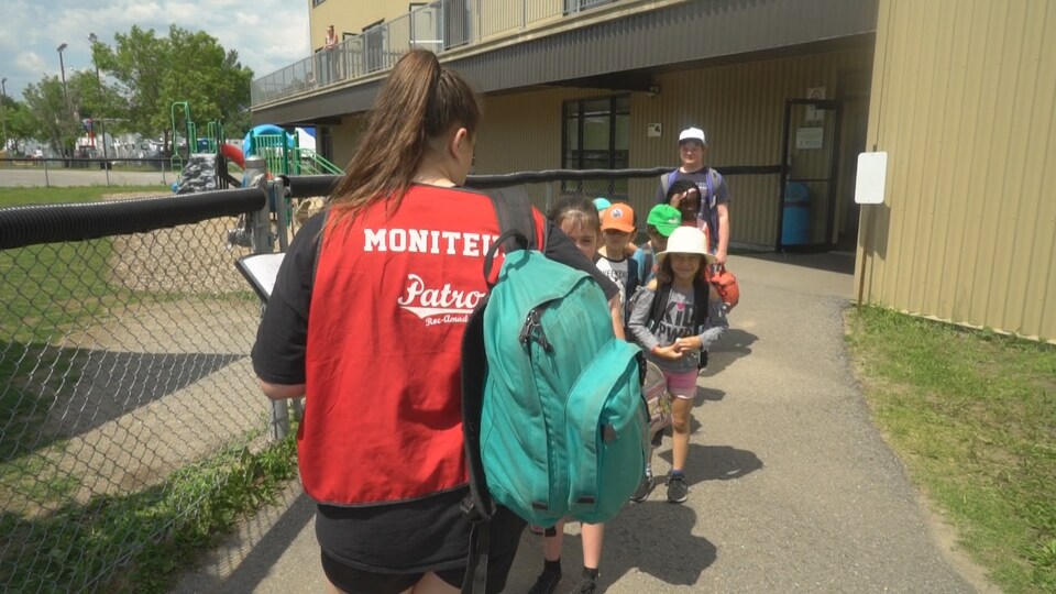 Une monitrice dehors avec des enfants.