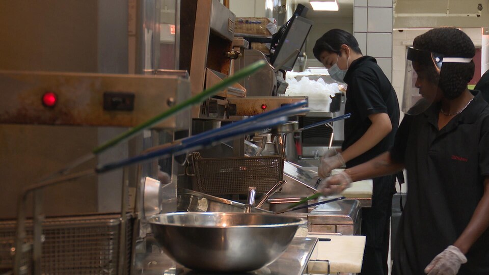 Deux cuisiniers aux fourneaux dans les cuisines d'un restaurant.