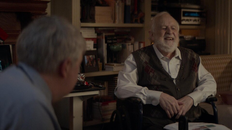 Une scène du court-métrage de Benoit Brière, Mourir en vie, avec Marcel Sabourin. Un vieillard rit dans son fauteuil roulant.