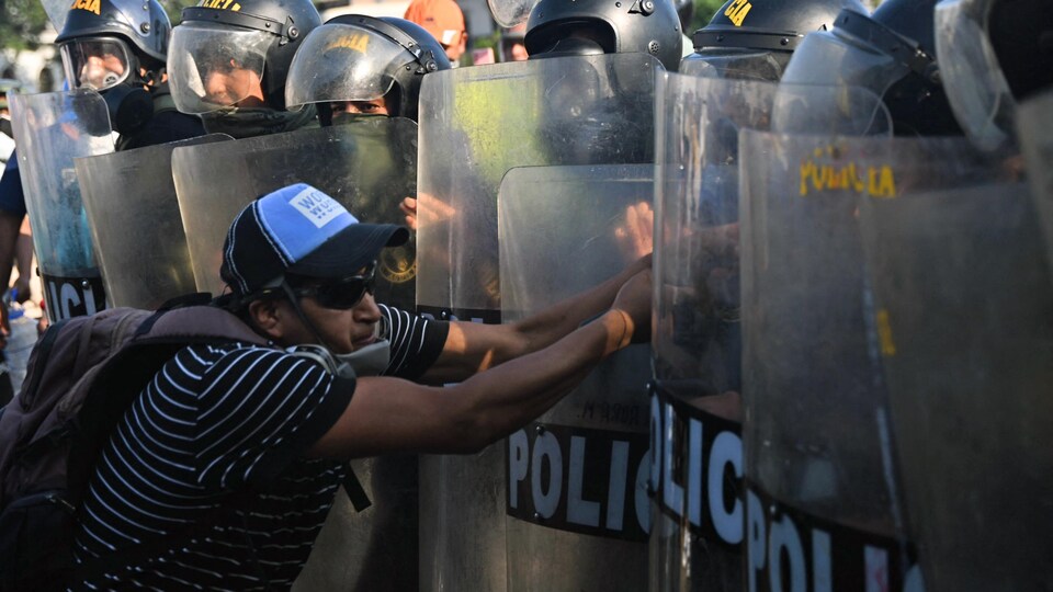 Un manifestant fait face à une rangée de policiers.