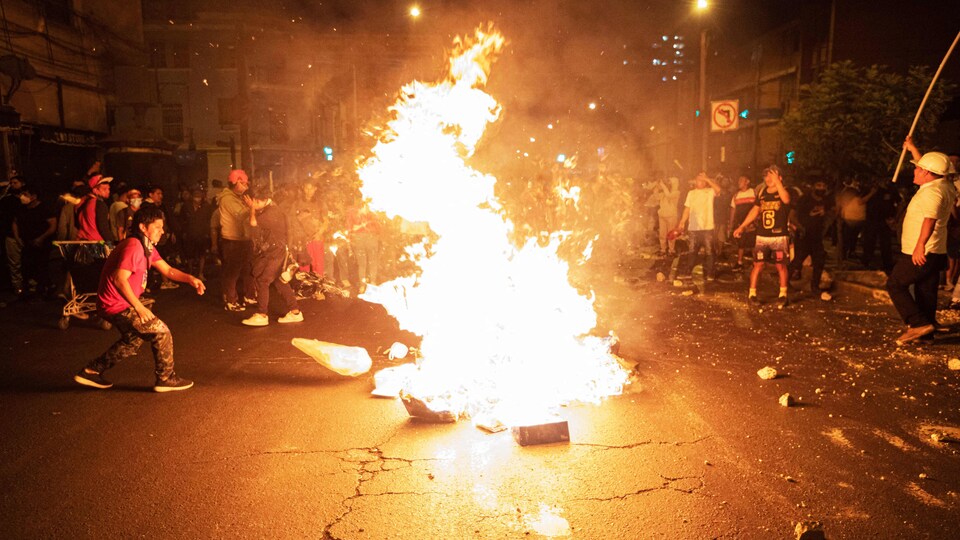 Des manifestants autour d'un feu au milieu d'une rue, la nuit