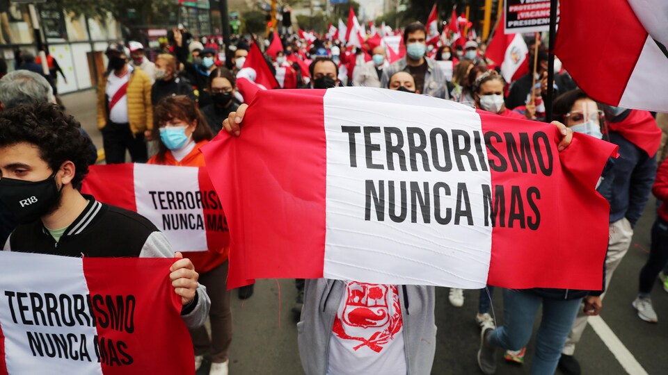 Les gens défilent avec des drapeaux péruviens où l'on peut lire : «le terrorisme, plus jamais».