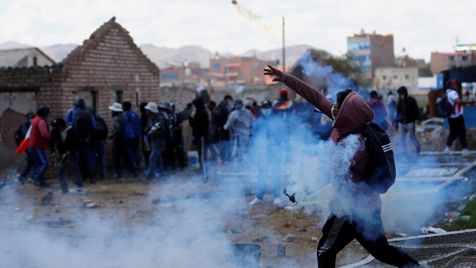Un émeutier lance une grenade fumigène.