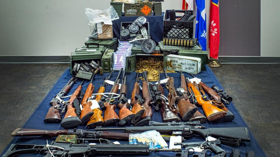 De nombreuses armes étalées sur une table de présentation de la police.