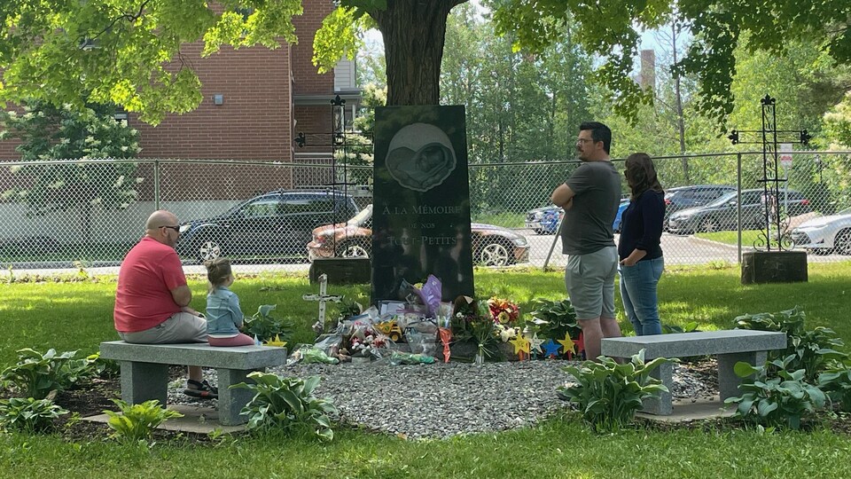 Des parents autour d'un monument commémoratif.