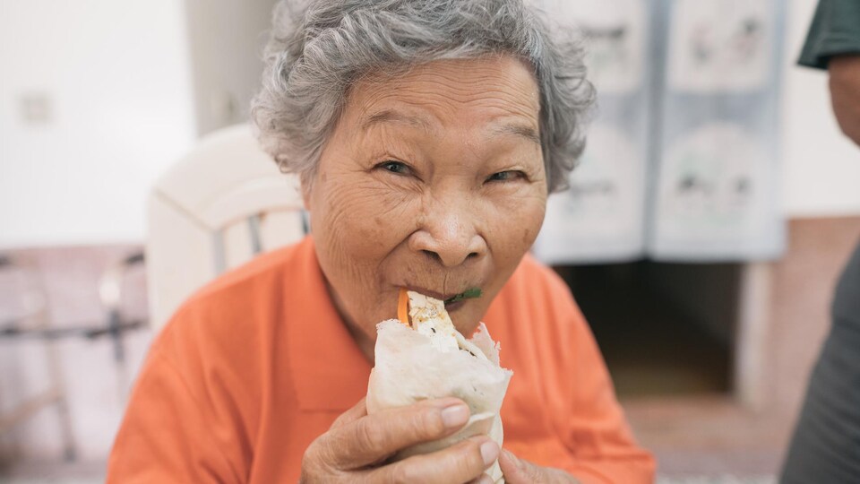 Une dame mange un rouleau de printemps.