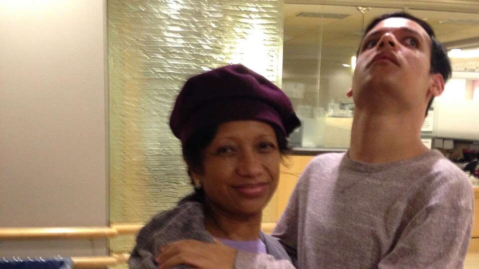 Une femme avec un béret sur la tête debout enlacé avec son fils de 31 ans.