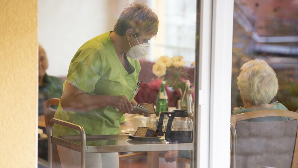 Une préposée sert du gâteau à une résidente de la maison de retraite St. Barbara à Stuttgart, dans le sud de l'Allemagne, le 17 novembre 2020.