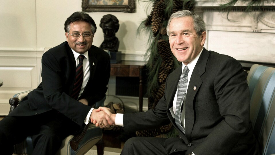 Pervez Musharraf et George W. Bush, assis, se serrant la main.