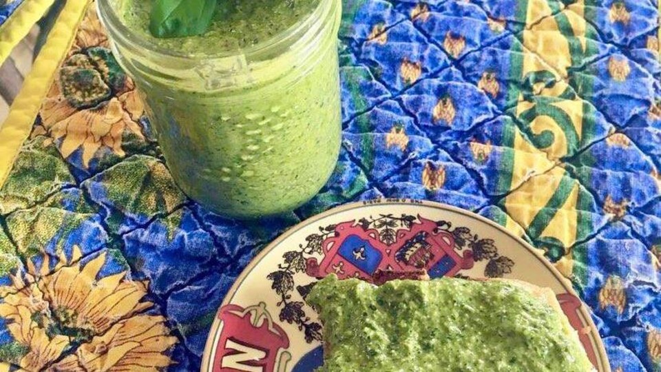 Un pot de pesto avec un morceau de pain.