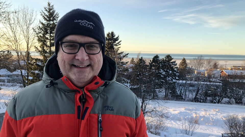 Peter Galbraith sourit à la caméra. Il est à l'extérieur, devant le fleuve Saint-Laurent, en hiver.