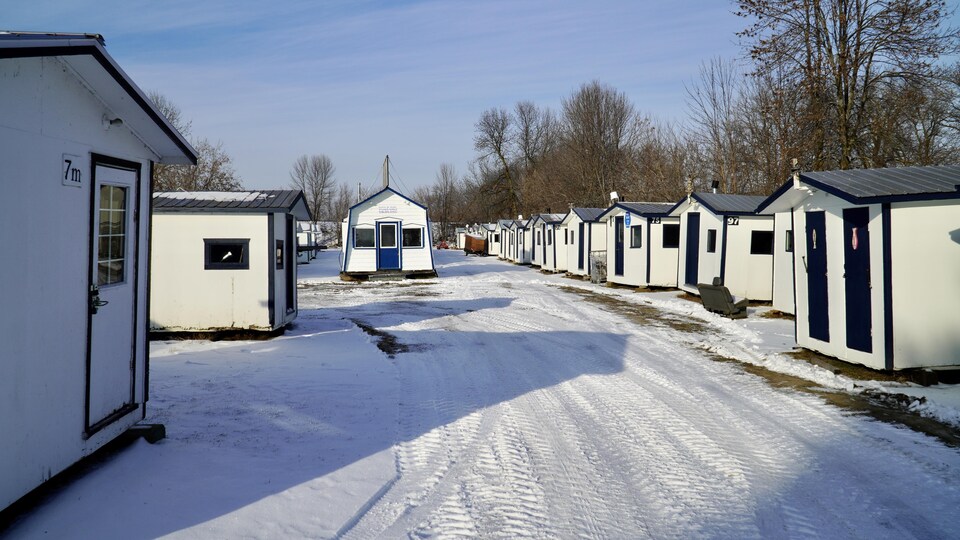 De petites cabanes de pêche bordant un chemin.