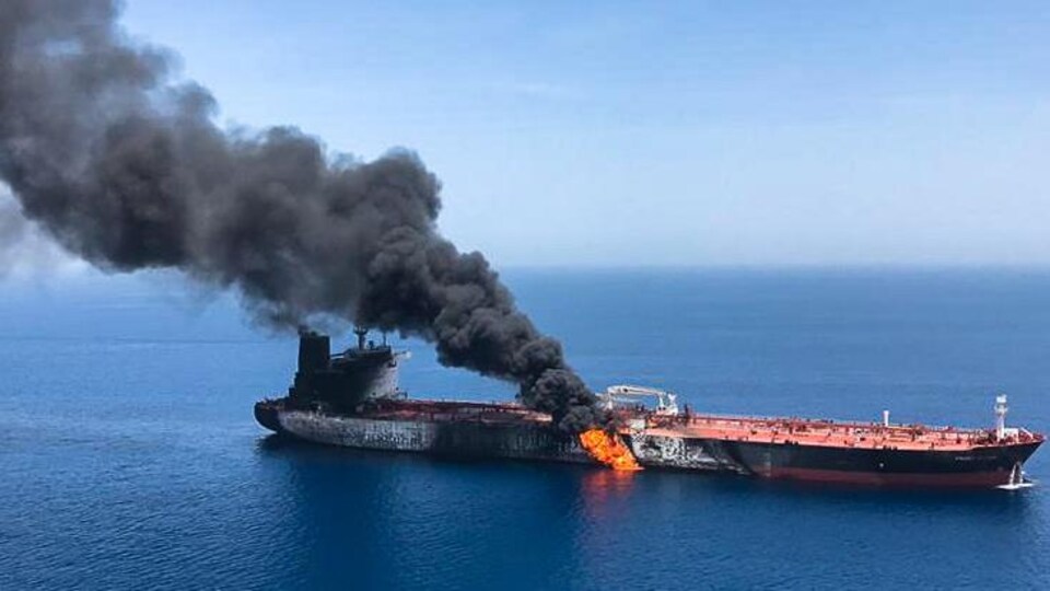 Des flammes et une colonne de fumée s'élèvent d'un pétrolier en mer.