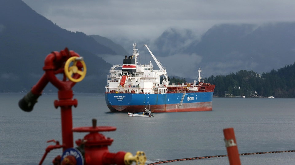 Un pétrolier est amarré au large d'une côte de la Colombie-Britannique sous un ciel nuageux.