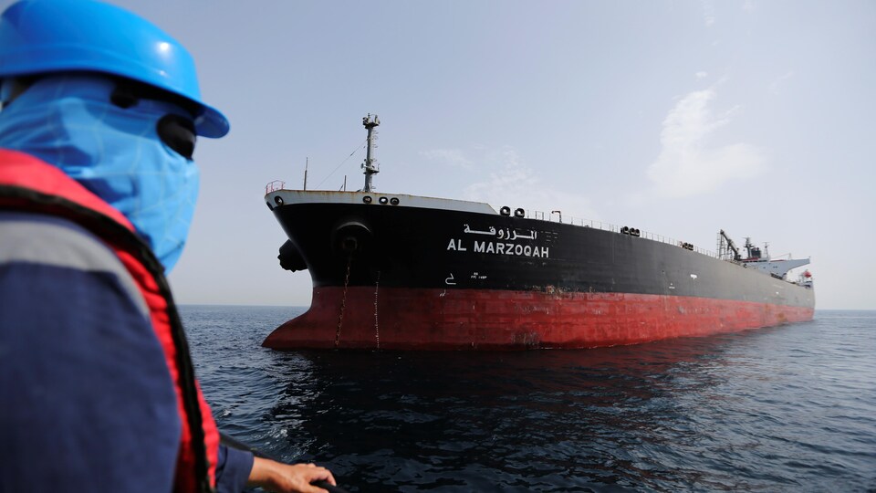 Un homme masqué regarde le pétrolier saoudien.