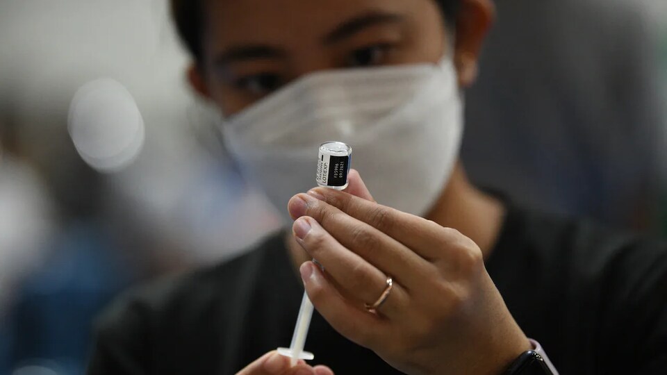 Un travailleur de la santé tient un vaccin contre la COVID-19.