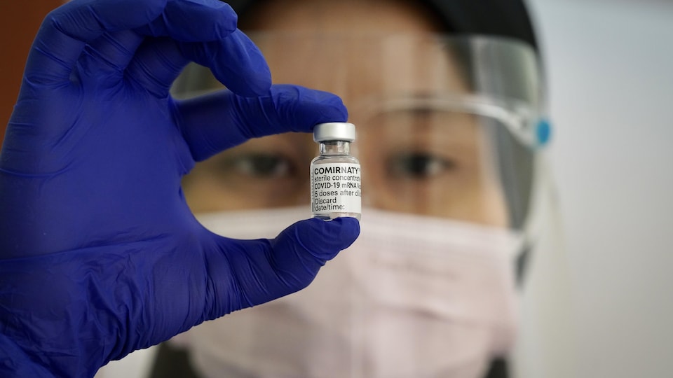 Un travailleur de la santé tient un flacon de vaccin contre la COVID-19 de Pfizer-BioNTech.