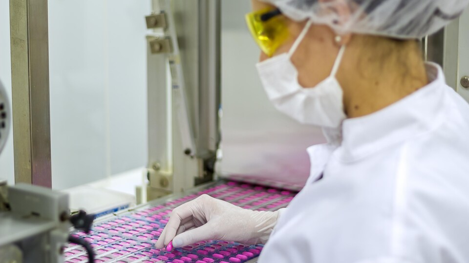 Une femme supervise la production et l'emballage de médicaments.