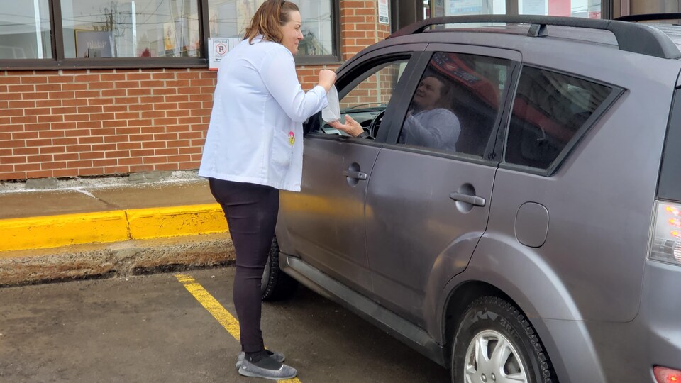 Une pharmacienne fait la livraison des médicaments à l'auto.