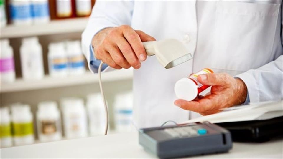 Un pharmacien scanne un code barre sur un flacon de médicaments.