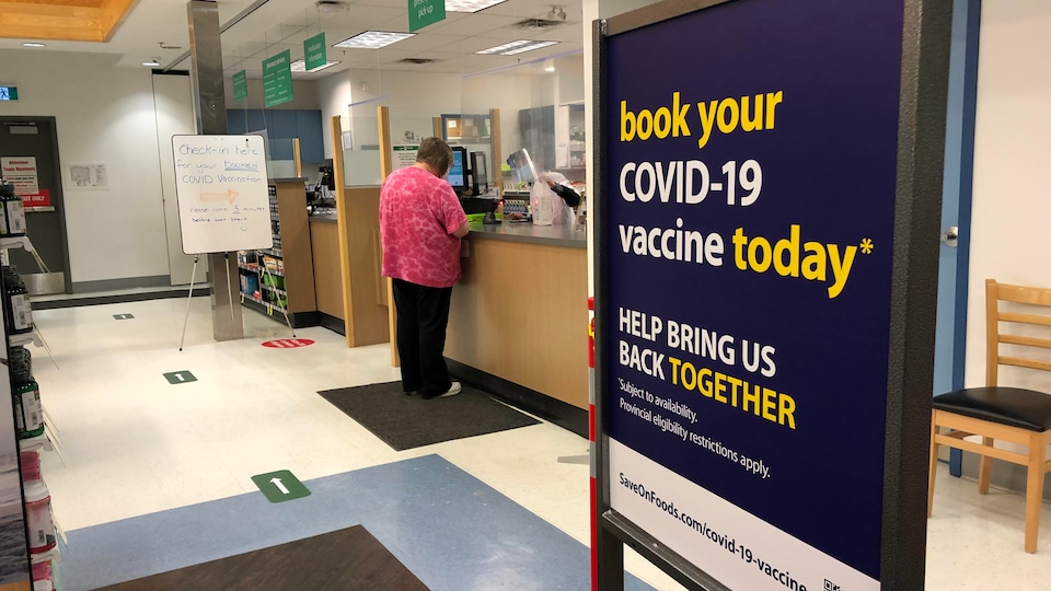 Un panneau devant le comptoir d'une pharmacie invite à prendre rendez-vous pour se faire vacciner.