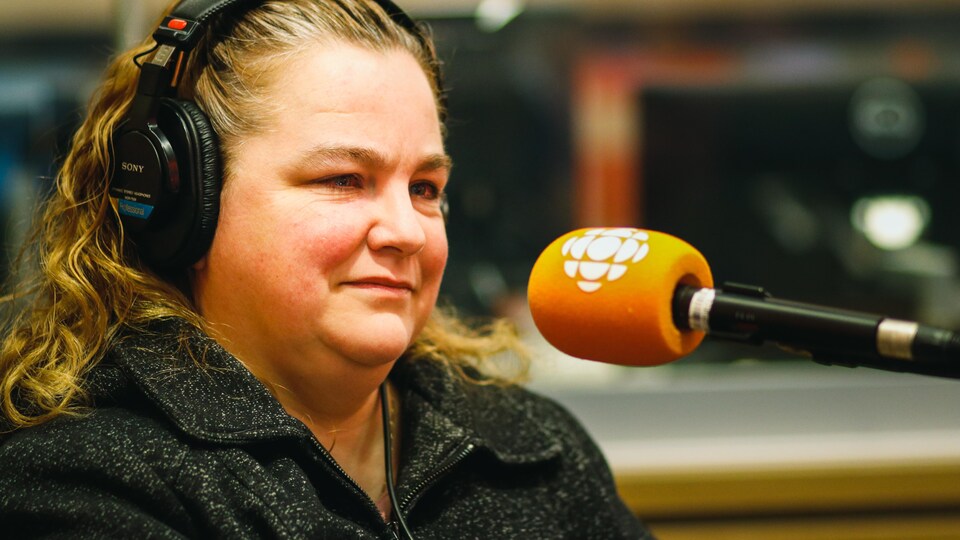 Une femme parle en studio à un micro.