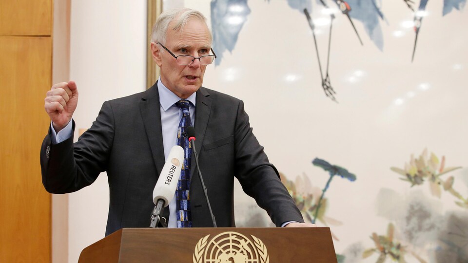 Philip Alston au micro derrière un lutrin arborant le symbole des Nations unies.