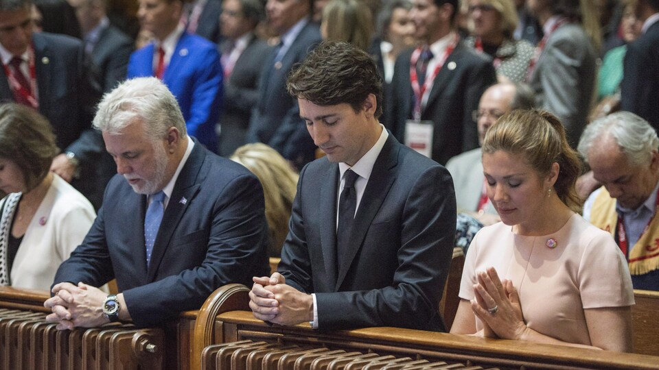 Les premiers ministres Philippe Couillard et Justin Trudeau, ainsi que Sophie Grégoire, prient lors d'une messe.
