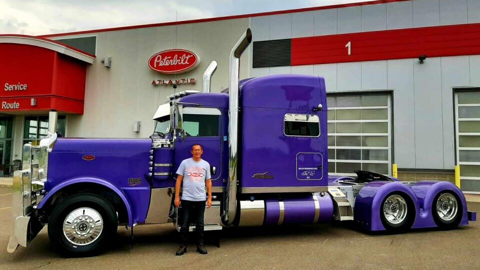 Philippe Guidon se tient devant son camion. Il est de couleur violette.